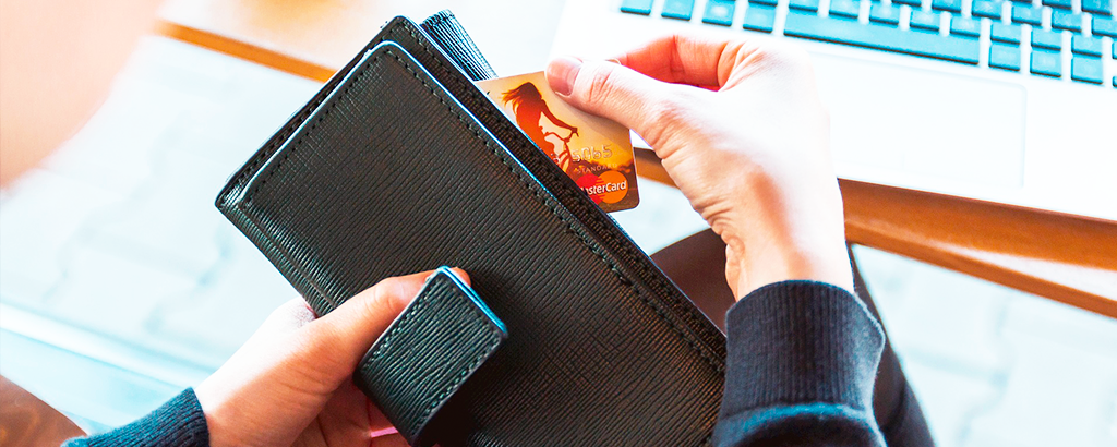 wallet with credit card gold and computer in the background