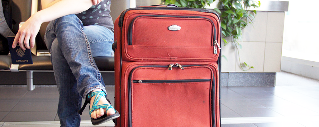 person waiting at the airport with a red baggage