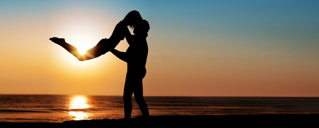 Man carrying his couple in front of the sea